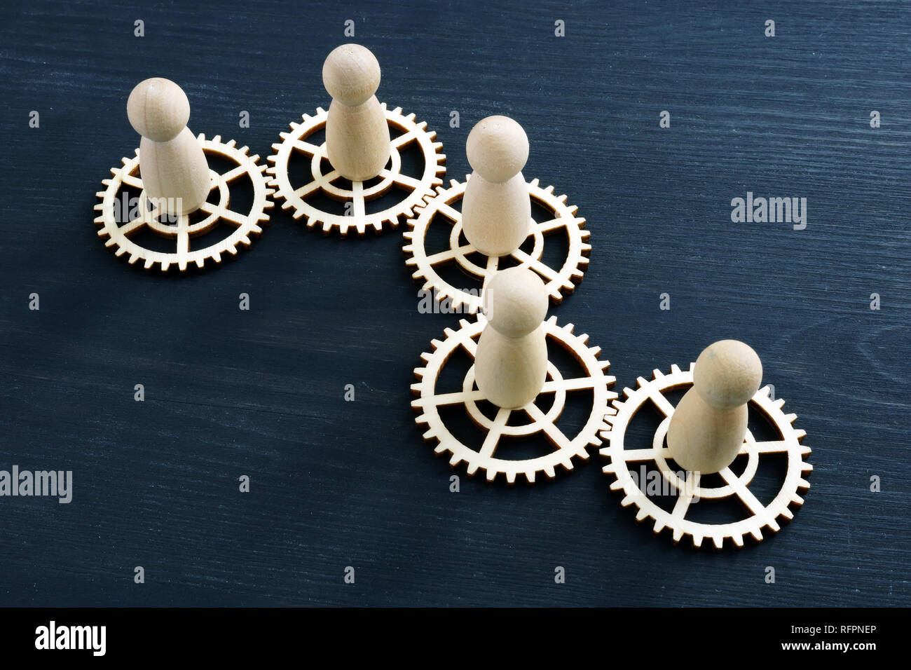 Teamwork success concept. Gear wheels and wooden figures. Stock Photo