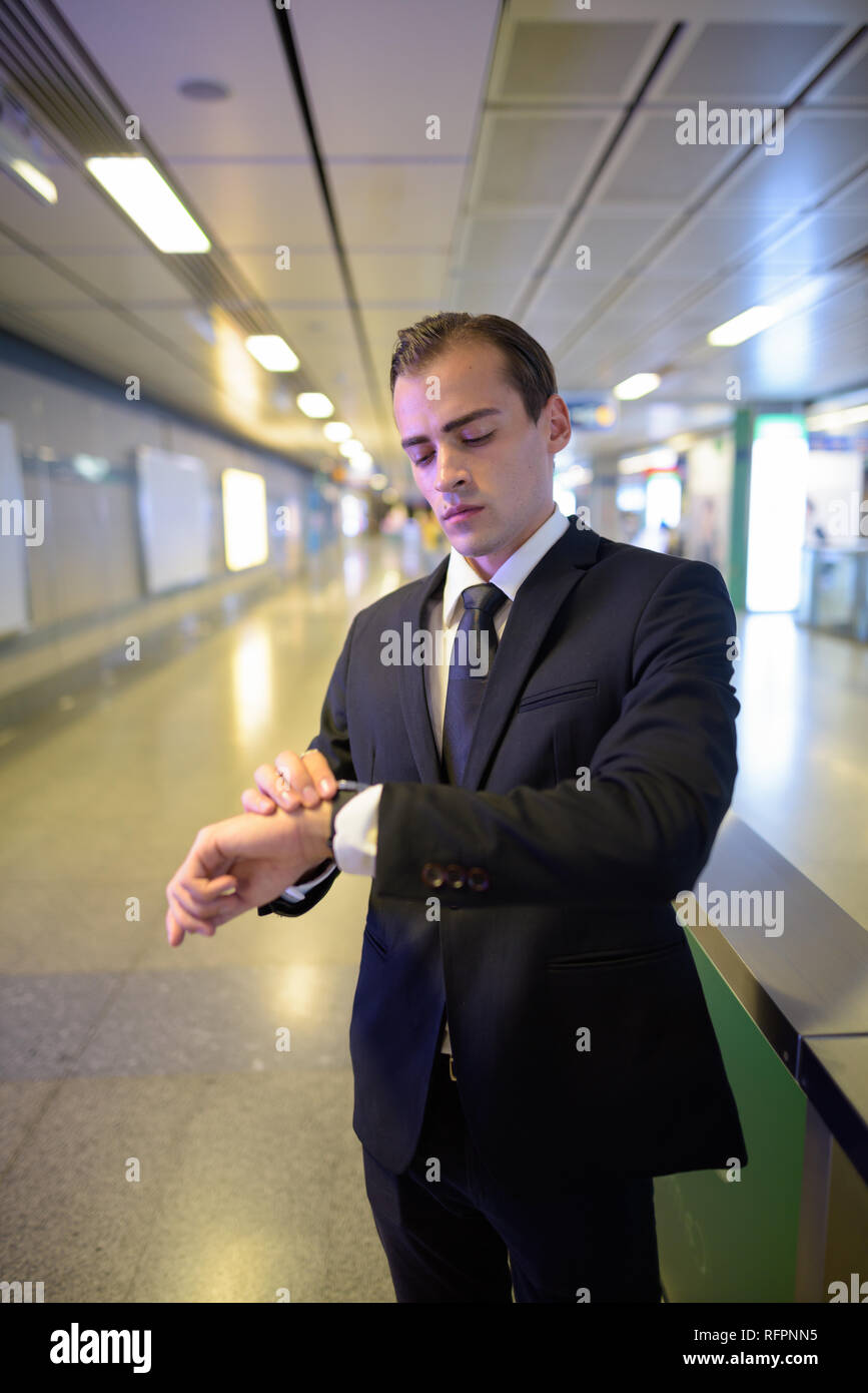 Young businessman checking time from watch at train station Stock Photo