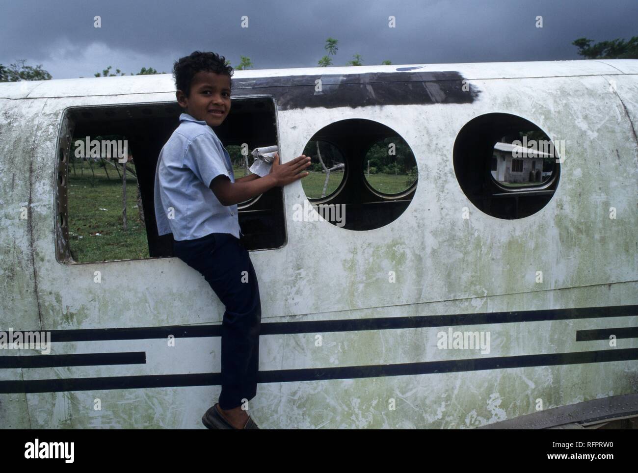 Boy playing in plane wreck, runway of Palacios, Moskitia, eastern Caribbean coast, Honduras Stock Photo