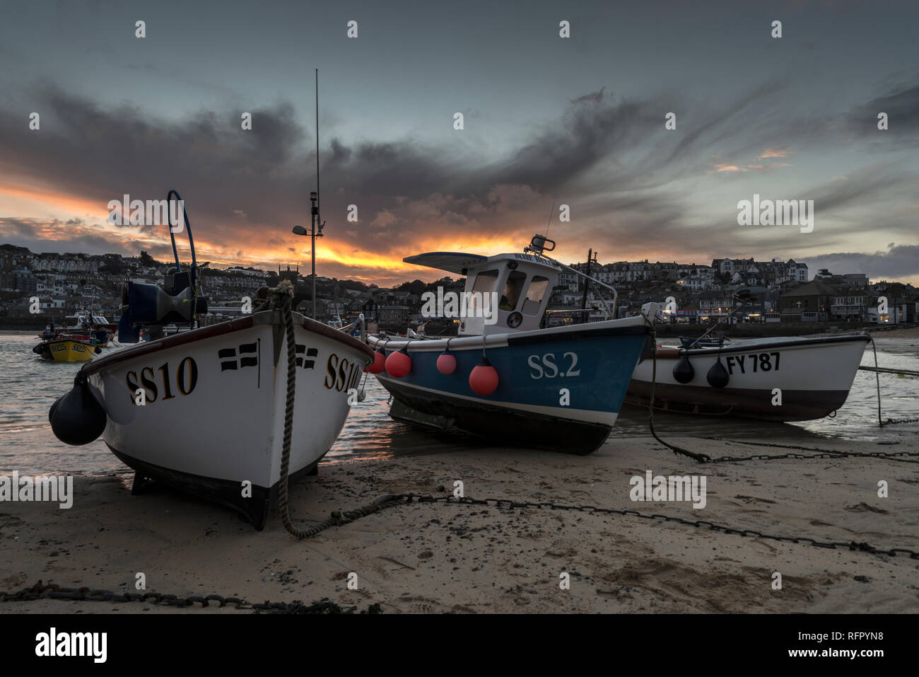 St.ives fishing boats on moorings in St.ives harbour at dusk with orange sky Stock Photo