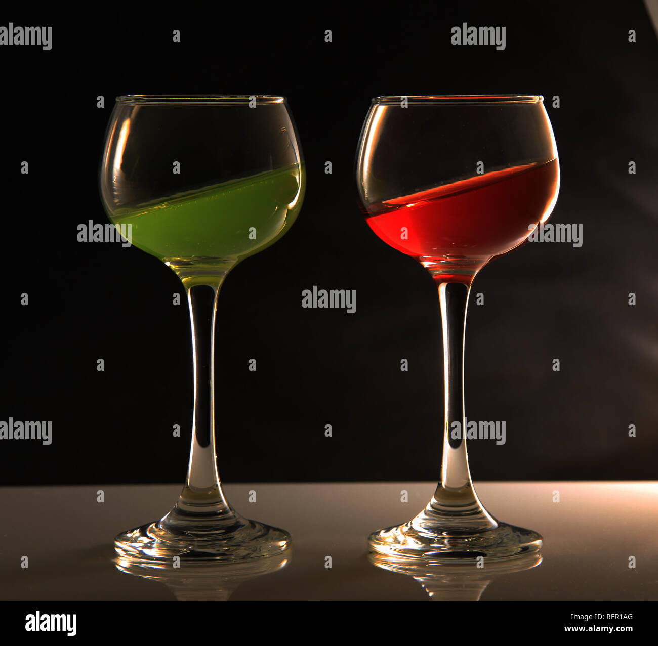 Wine glasses with different coloured liquids tilted at an angle Stock Photo