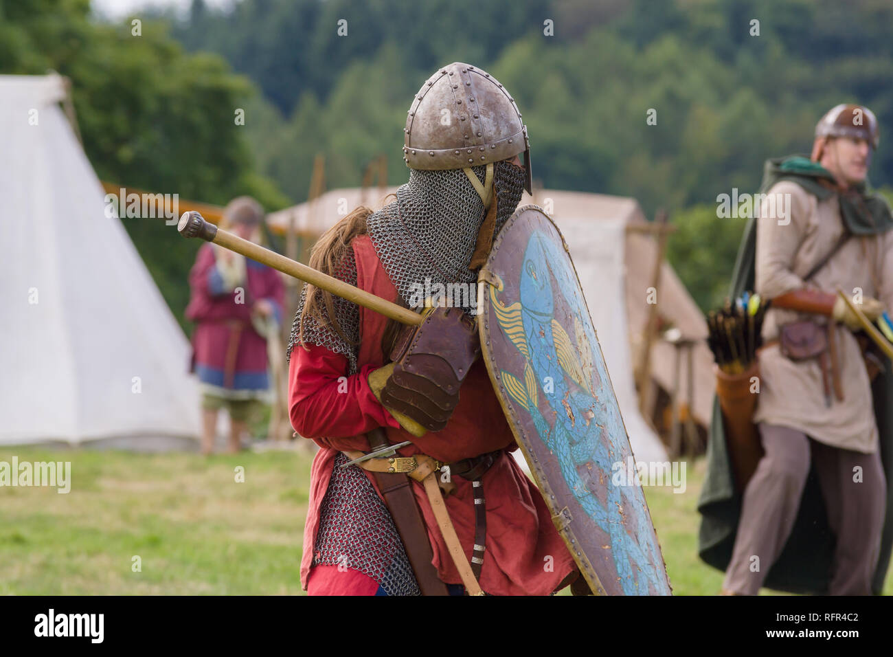 Medieval battle re-enactment with men wearing a spangenhelm helmet and chain mail aventail or camail to protect the neck with a mace Stock Photo