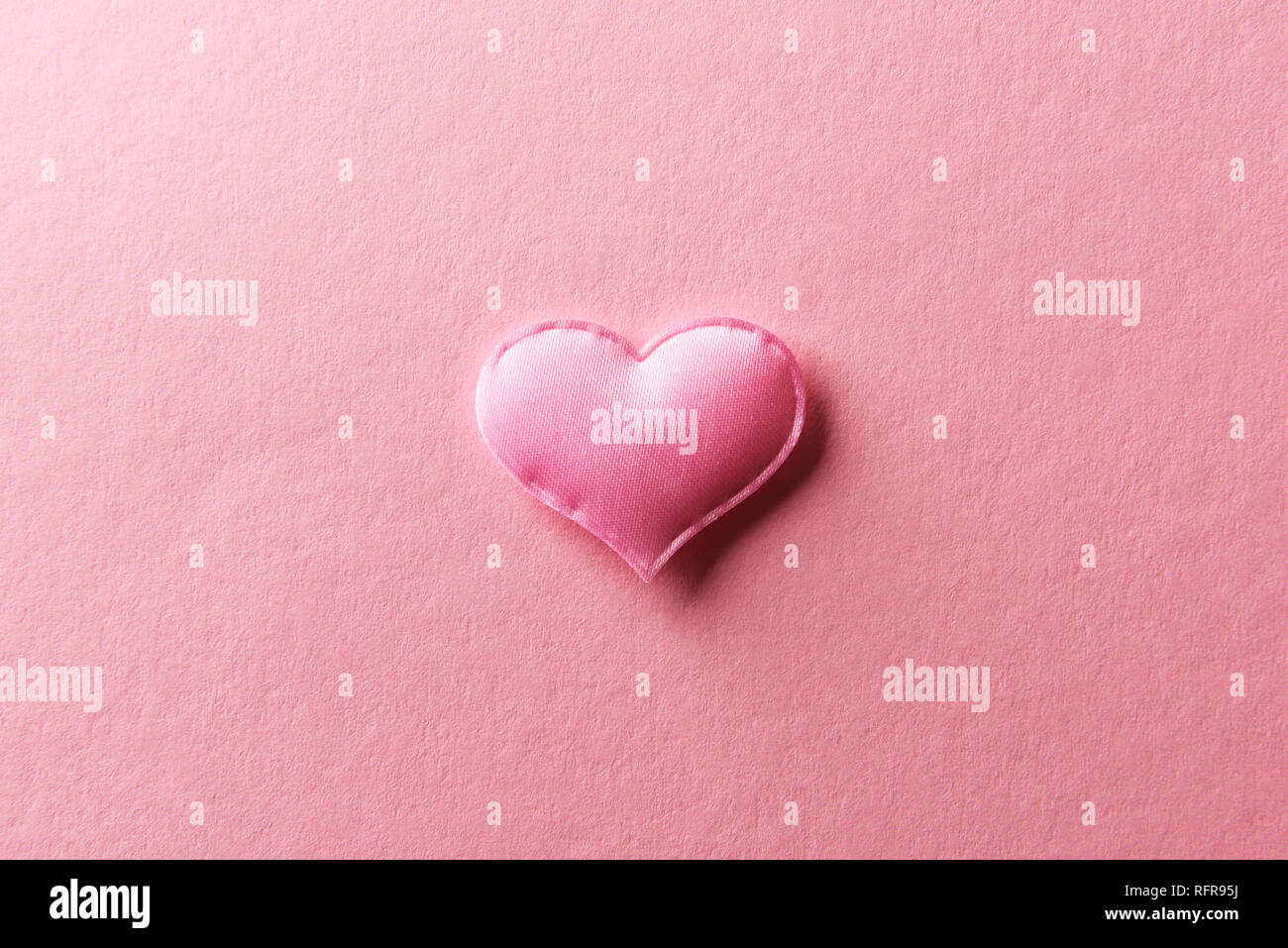 Pink textile heart on pink background. Valentines day texture and love concept Stock Photo