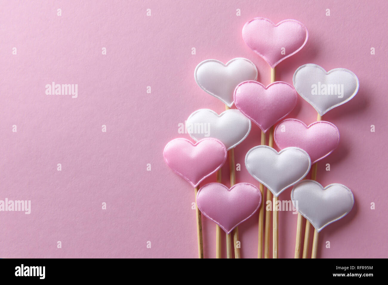 Pink textile hearts on wooden sticks closeup. Valentines day background, creative texture and love concept Stock Photo
