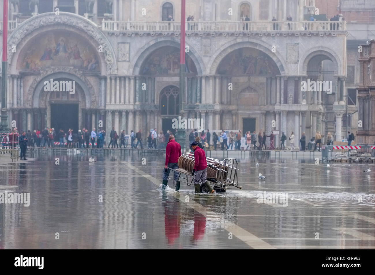 San Marco Square, Piazza San Marco, with workers pulling loads, flooded during the Acqua alta Stock Photo