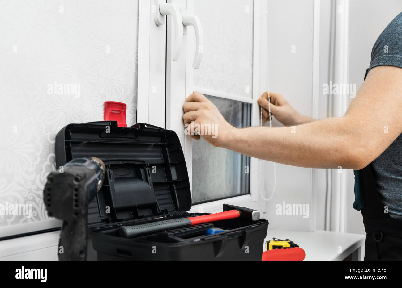 Man testing cassette roller blinds on windows. Stock Photo