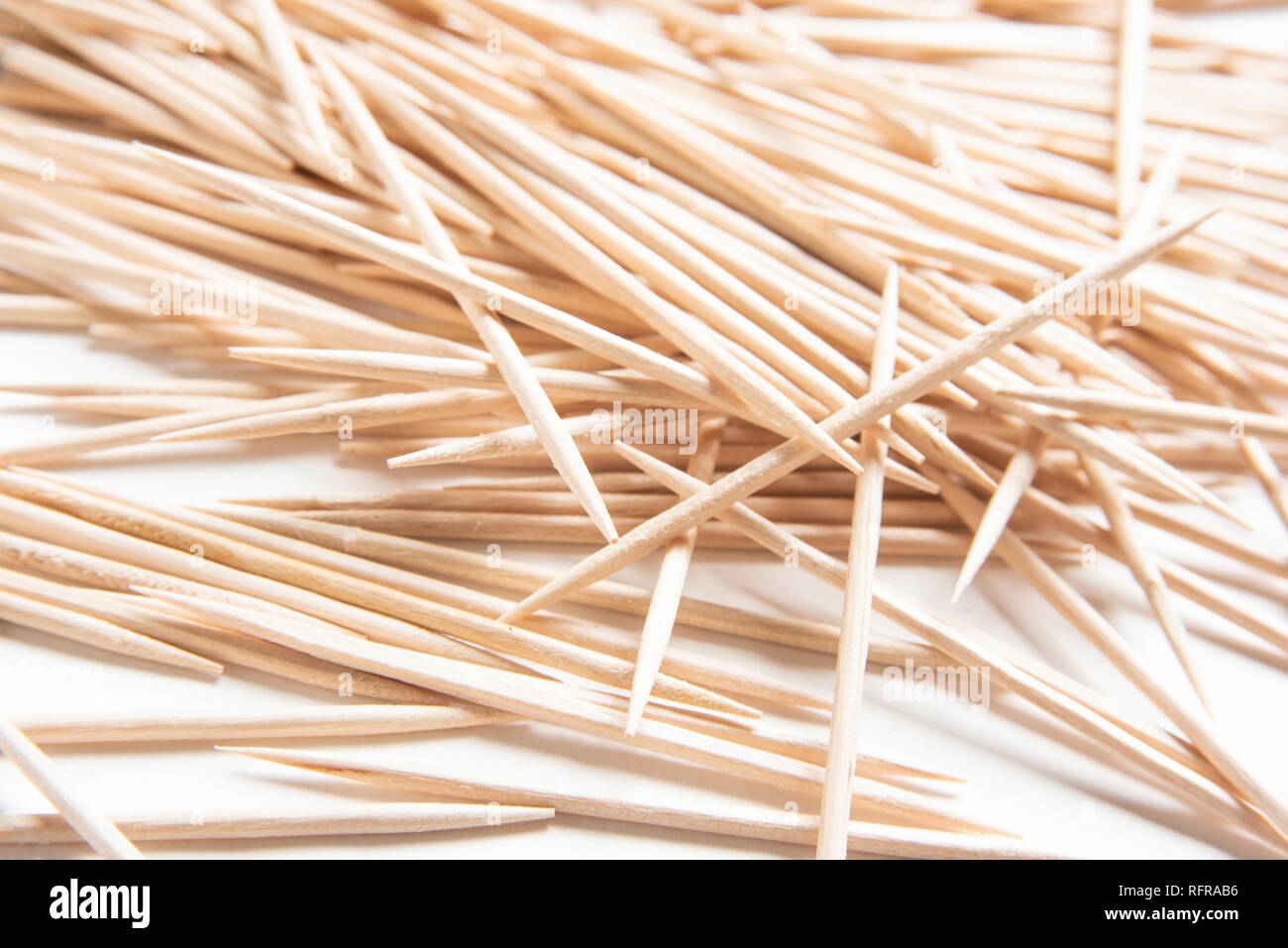 A bunch of unused round wooden toothpicks artfully scattered on a plain ...