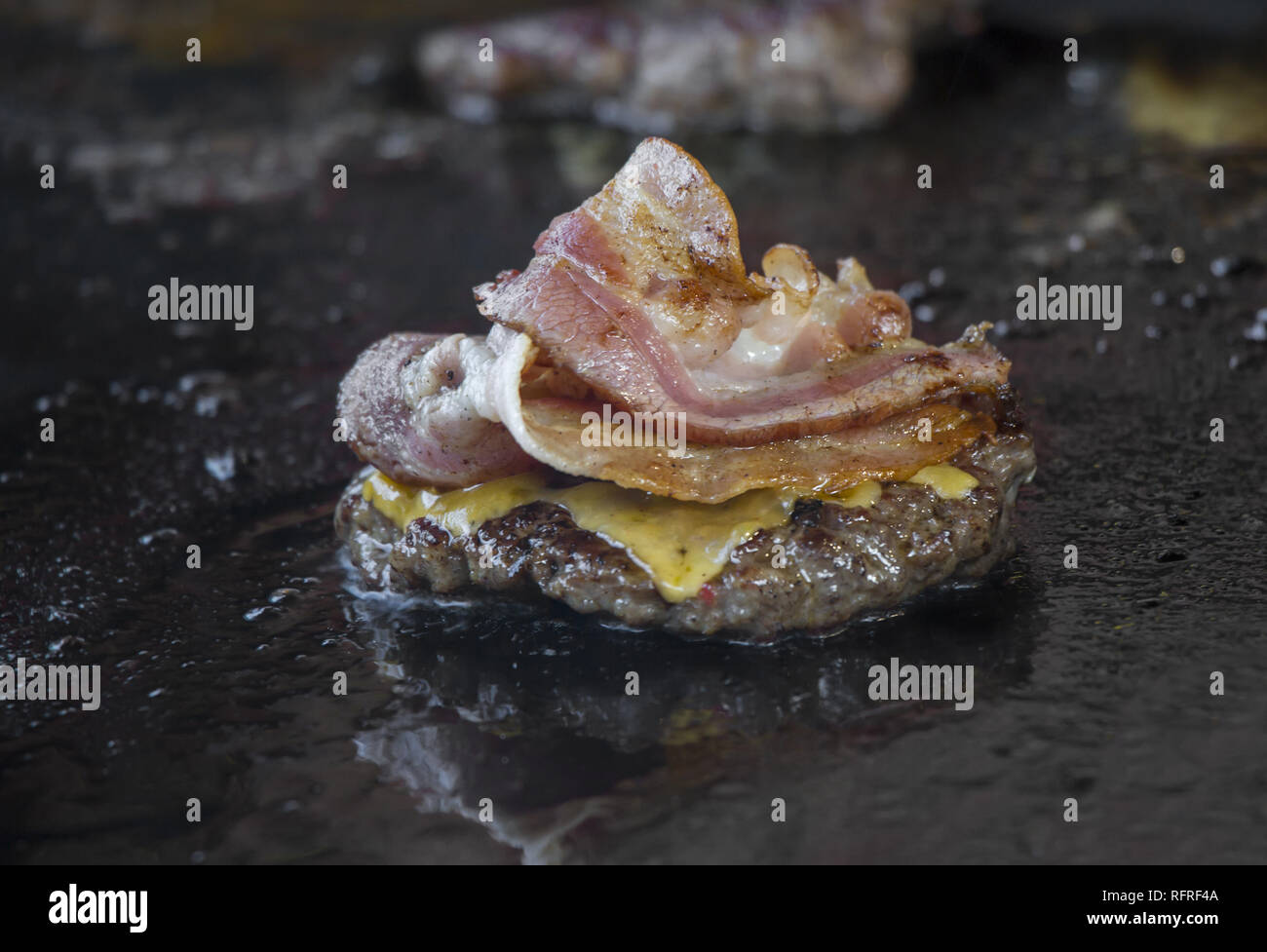Preparing burgers with bacon at the barbecue outdoors Stock Photo