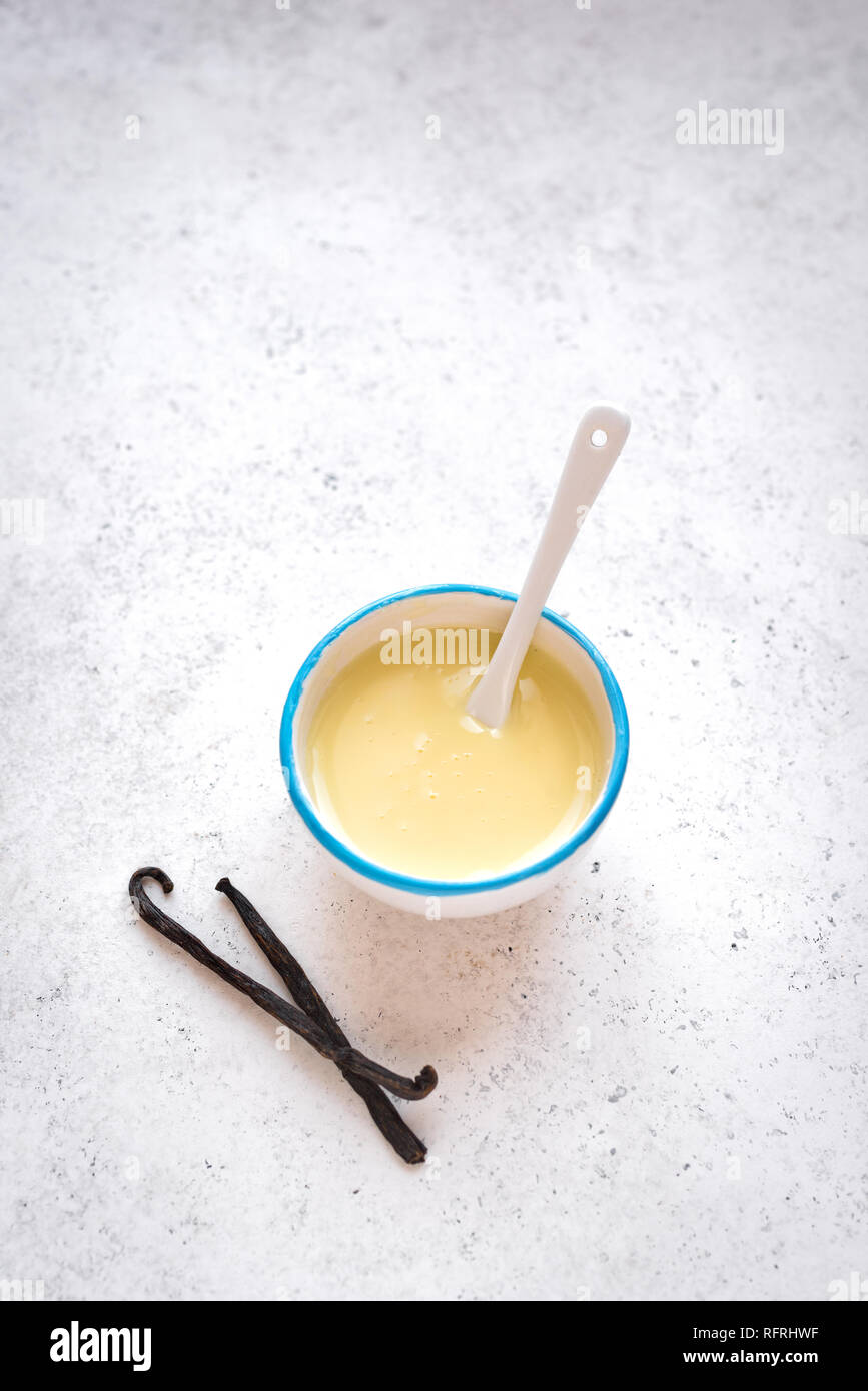 Vanilla sauce pouring in white bowl. Sweet condensed or evaporated milk
