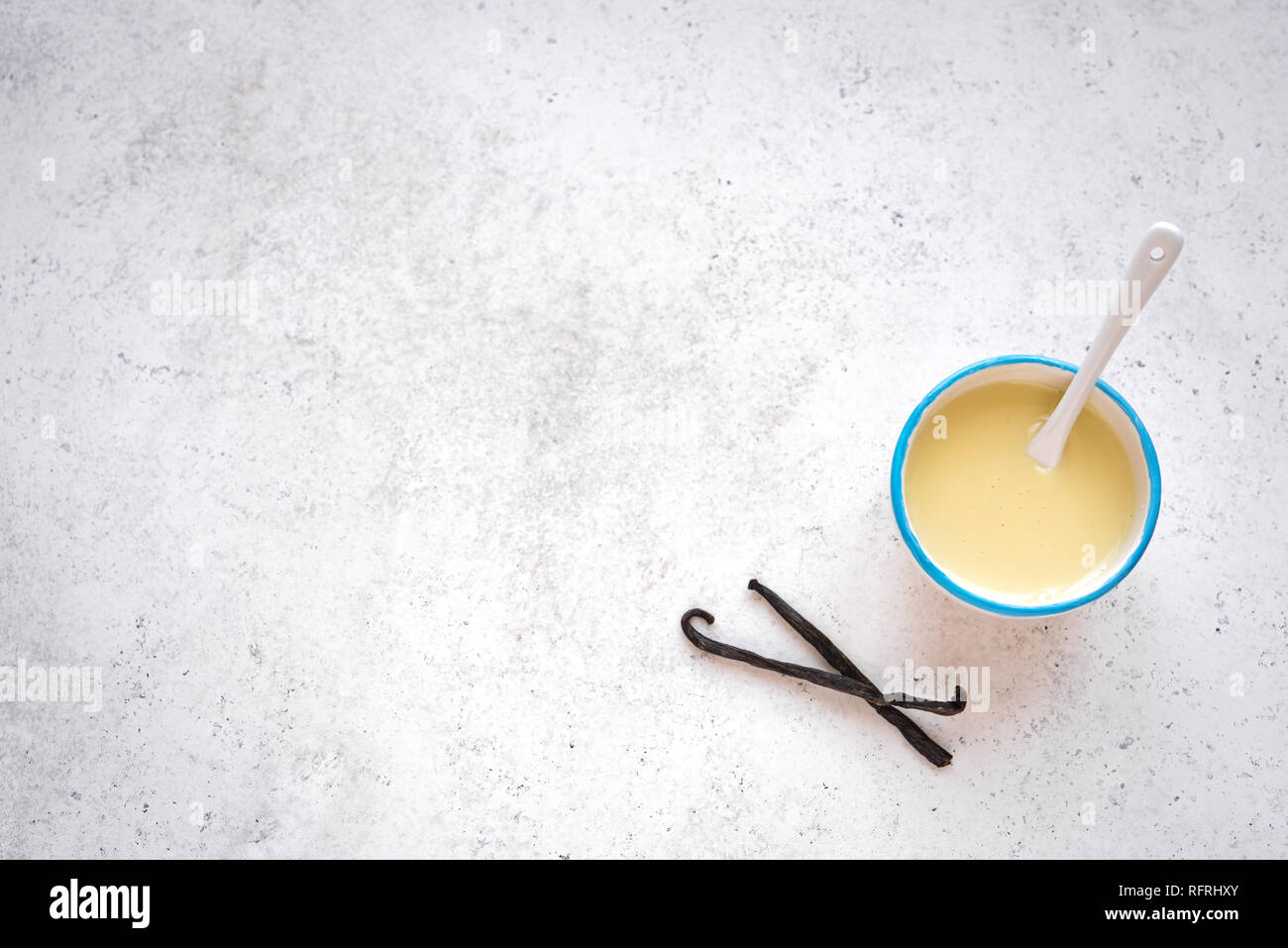 Vanilla sauce pouring in white bowl. Sweet condensed or evaporated milk