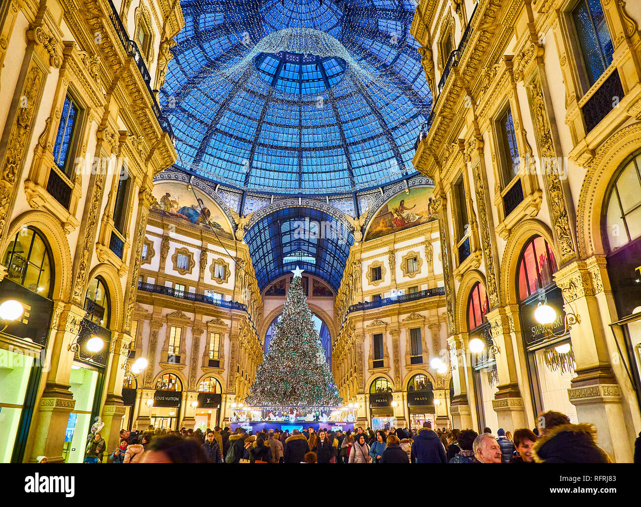 People walking on The Galleria Vittorio Emanuele II illuminated by christmas lights and a shinny christmas tree. Milan, Lombardy, Italy. Stock Photo