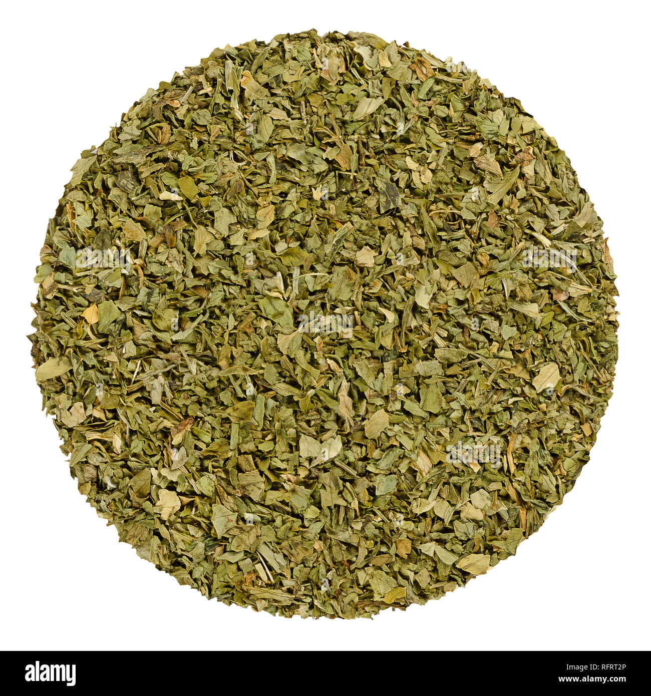 Dried lovage. Herb circle from above, isolated, over white. Disc made of grated lovage leaves, Levisticum officinale. Edible green herb and vegetable. Stock Photo