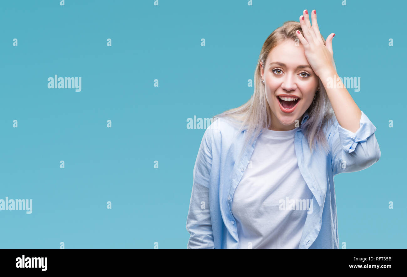 Young blonde woman over isolated background surprised with hand on head ...