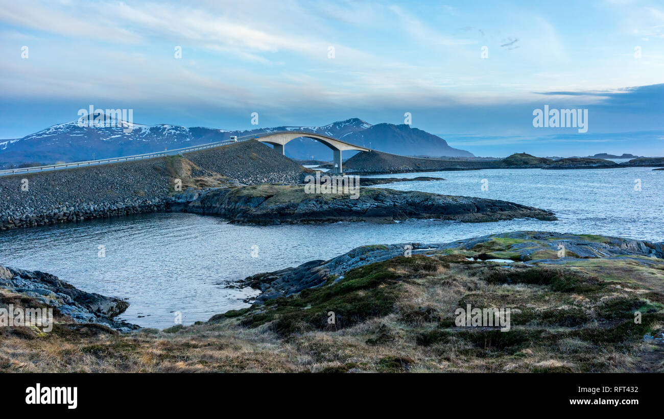 View of the Storseisundet Bridge with mountains in the background from Eldhusøya on the Atlantic Road in Norway Stock Photo