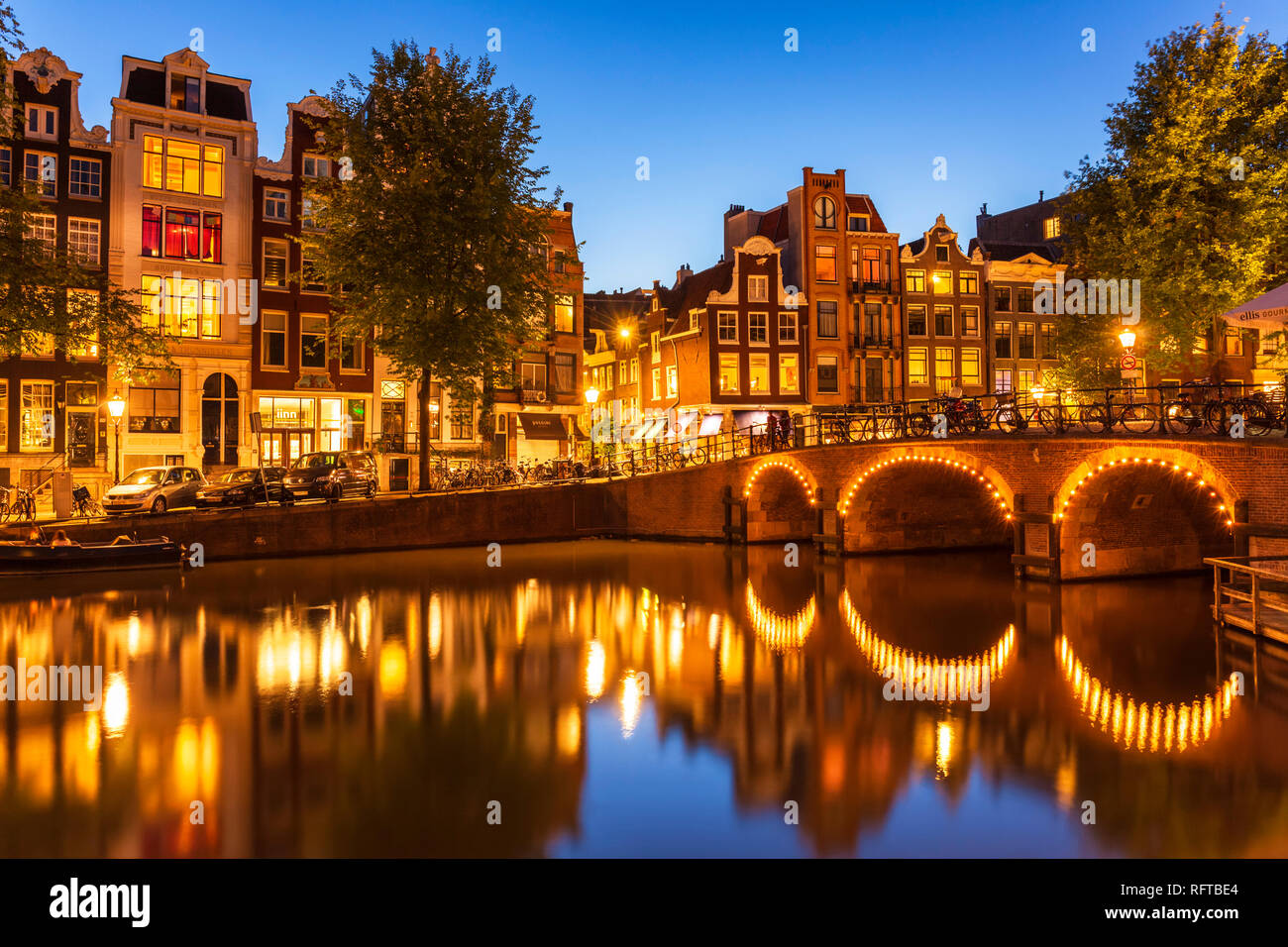 Illuminated canal bridge with reflections at night over the Singel Torensluis canal, Amsterdam, North Holland, Netherlands, Europe Stock Photo