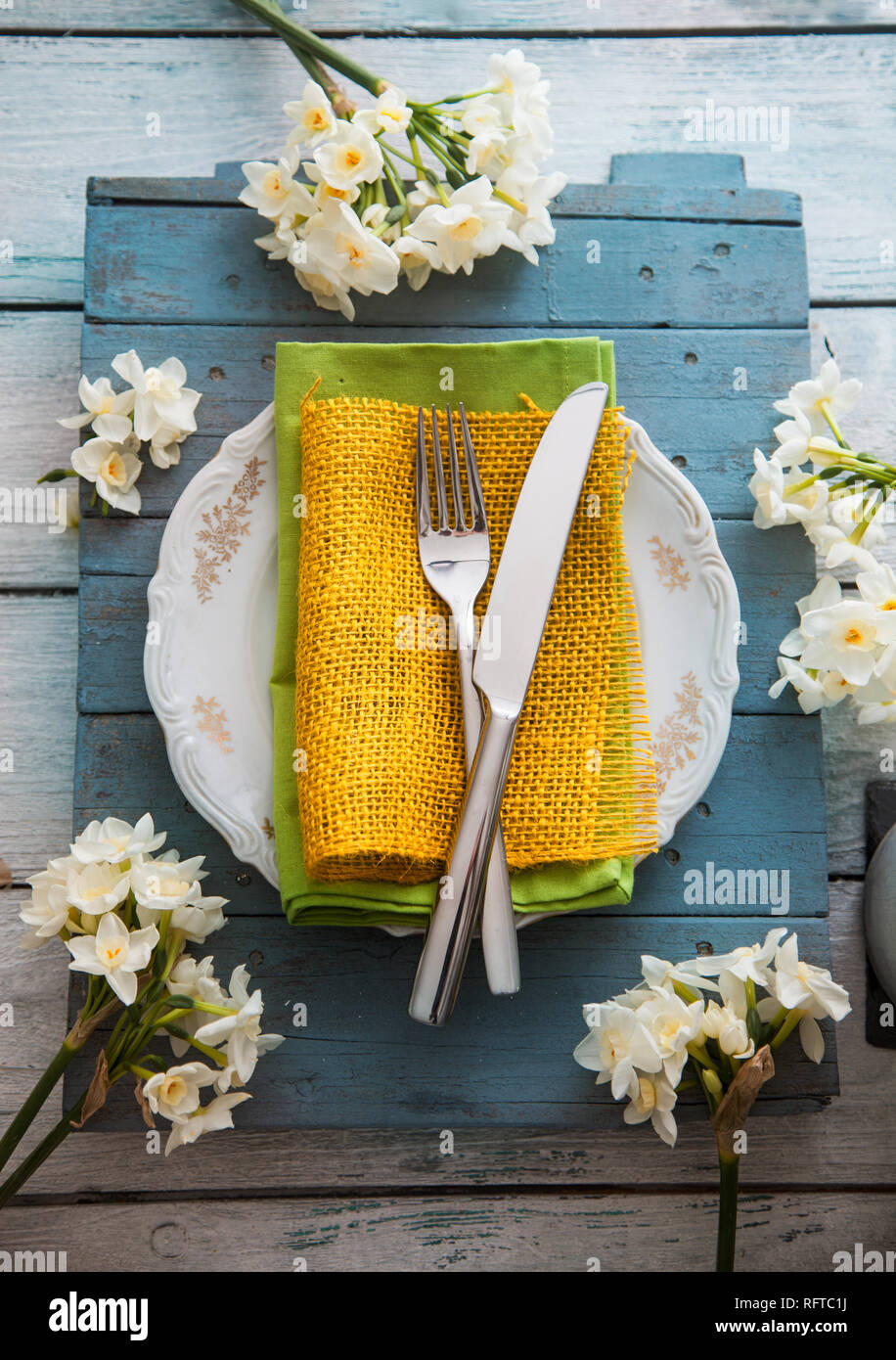 Spring table setting. Narcissus flower. Fork and knife on Easter table. Holiday table setting. Top flatlay ovehead view Stock Photo