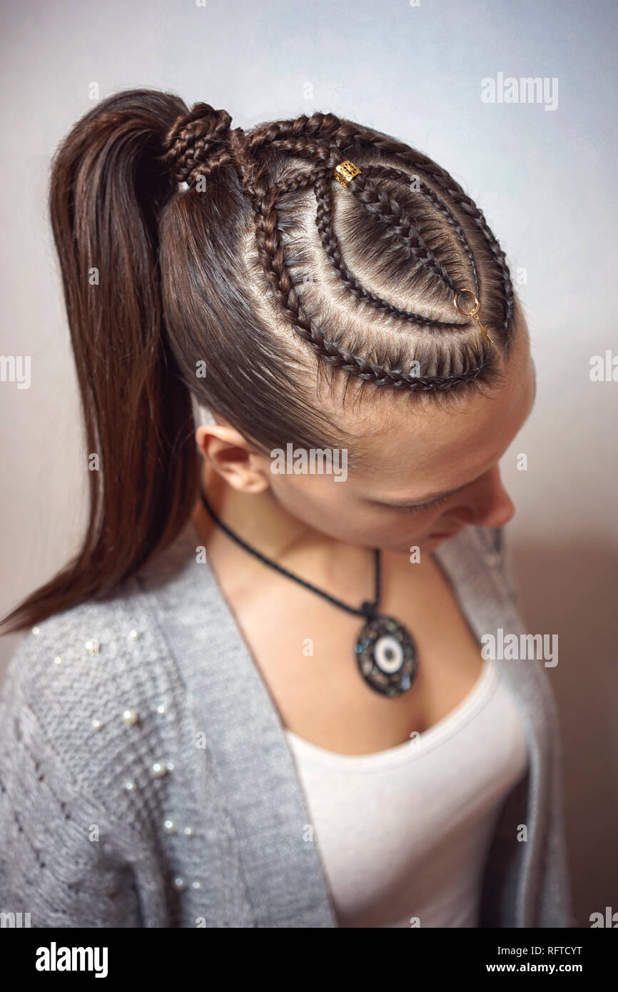 cornrows hairstyle for a girl with dark hair, thin braids tied in a tail Stock Photo