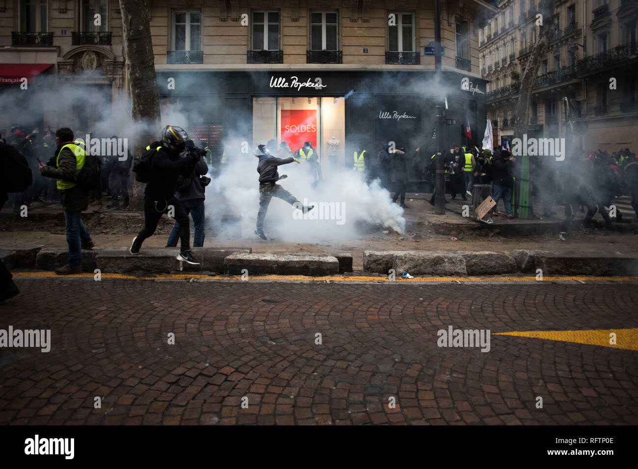 A yellow vest protestor throws back the tear gas cannister to the police (not pictured) during a demonstration against macron policies. Yellow vest protestors gathered and march on the streets of Paris another Saturday on what they call the Act XI against the French president Emmanuel Macron policies. Stock Photo