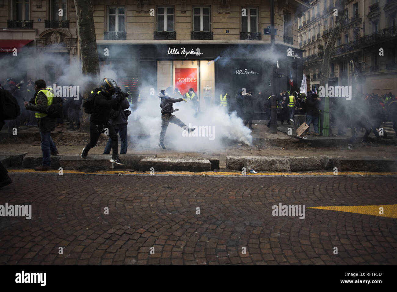 Paris, Ile de France, France. 26th Jan, 2019. A yellow vest protestor throws back the tear gas cannister to the police (not pictured) during a demonstration against macron policies. Yellow vest protestors gathered and march on the streets of Paris another Saturday on what they call the Act XI against the French president Emmanuel Macron policies. Credit: Bruno Thevenin/SOPA Images/ZUMA Wire/Alamy Live News Stock Photo