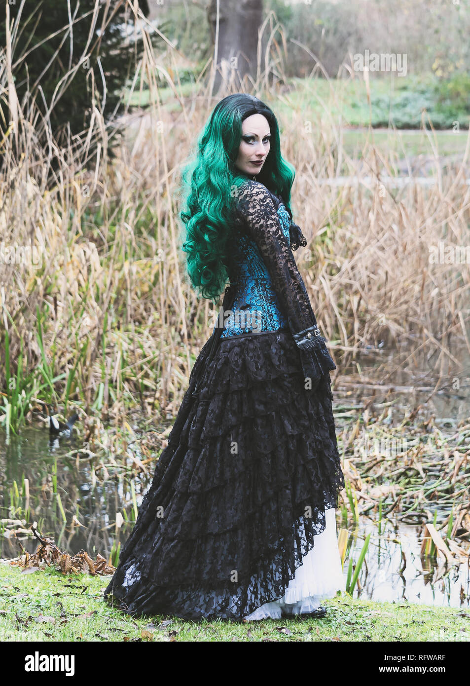 Gothic Victorian lady with blue corset and green hair. Walking in a park. Winter time. Stock Photo