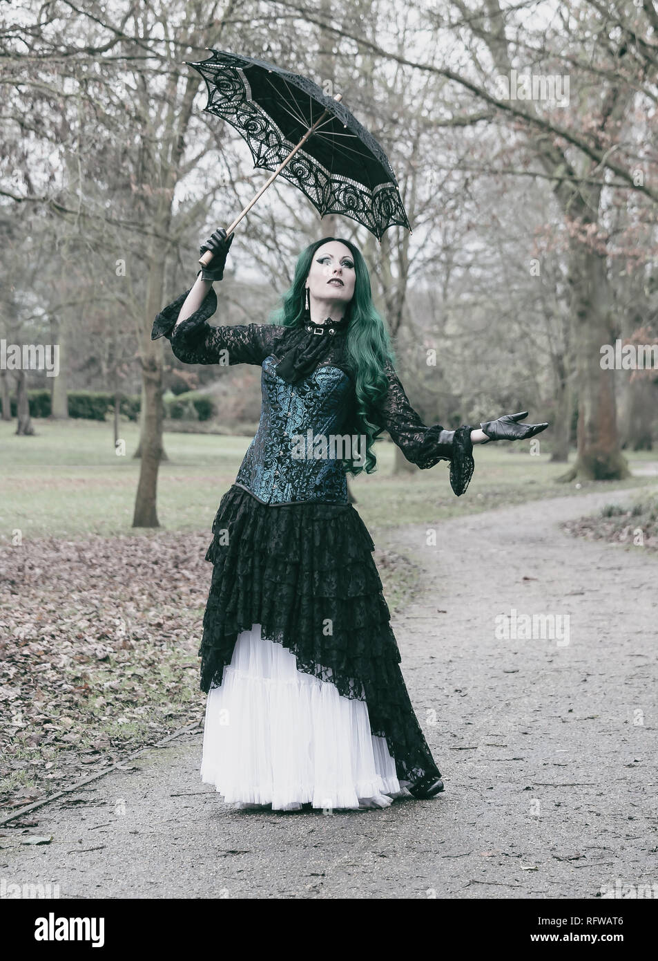 Gothic Victorian lady with blue corset and green hair. Walking in a park. Winter time. Stock Photo