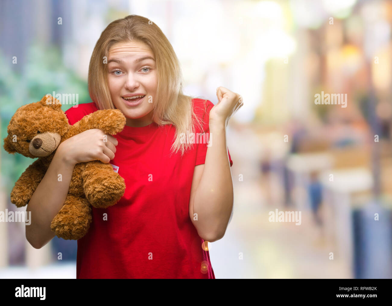 Young caucasian woman holding cute teddy bear over isolated background ...