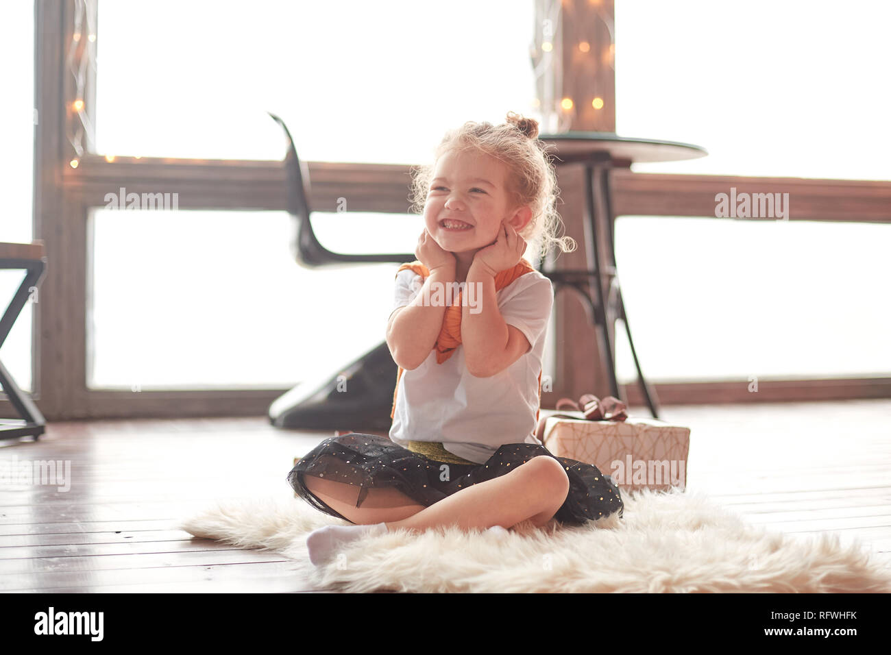 happy little girl sitting on the carpet in the living room Stock Photo ...