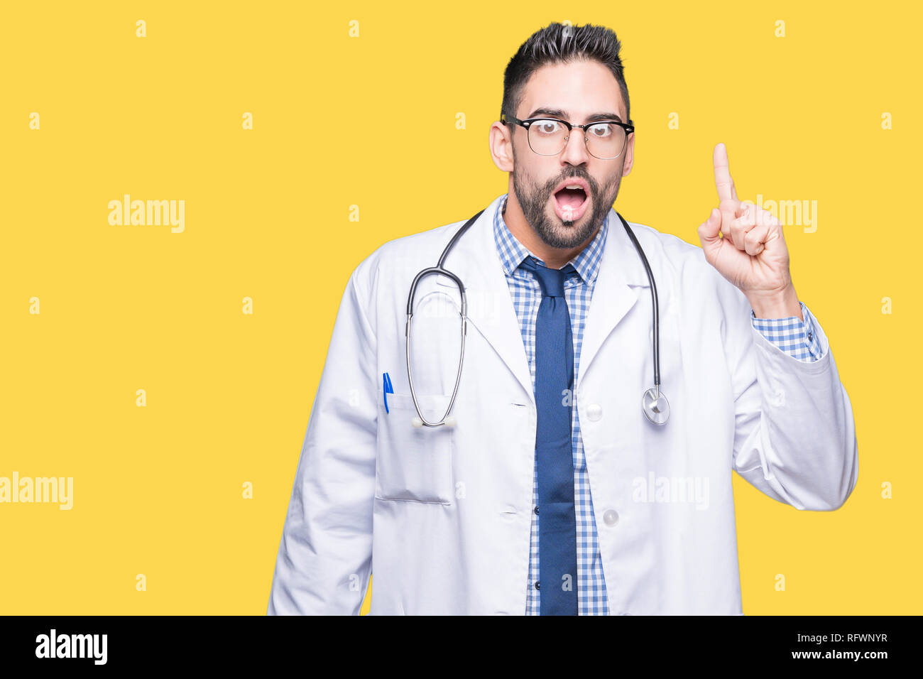 Handsome young doctor man over isolated background pointing finger up with successful idea. Exited and happy. Number one. Stock Photo