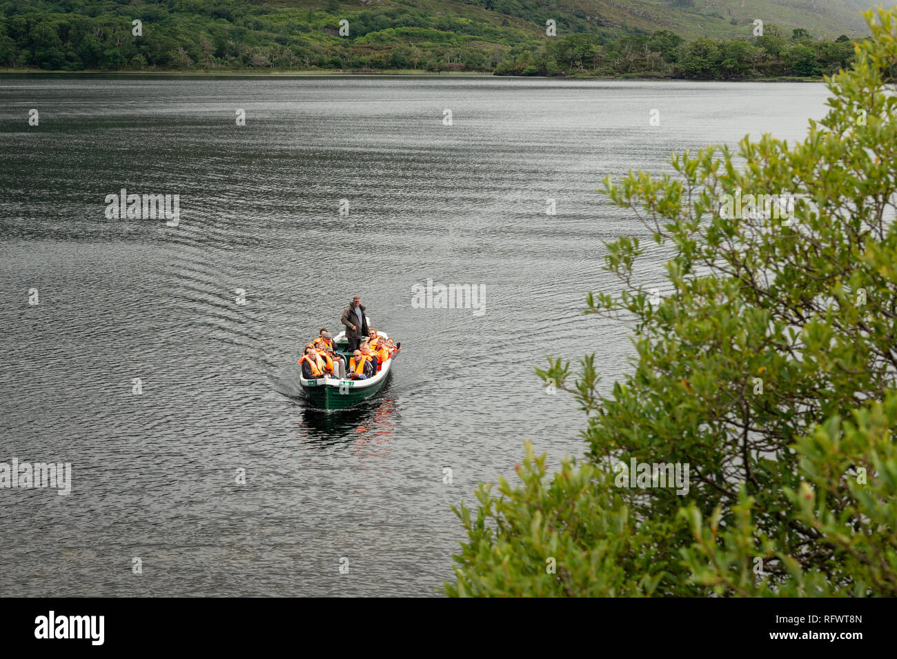 Lakes of Killarney boat trip and tourists in rowing motorboat on the mountain Muckross lake in Killarney National Park, County Kerry, Ireland. Stock Photo