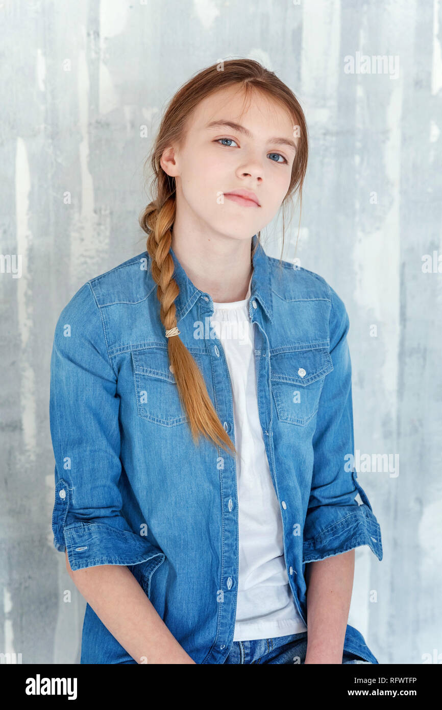 Young happy cute teenage girl in jeans, denim jacket and white T-shirt  sitting on chair against grey textured wall background. Casual daily  lifestyle Stock Photo - Alamy