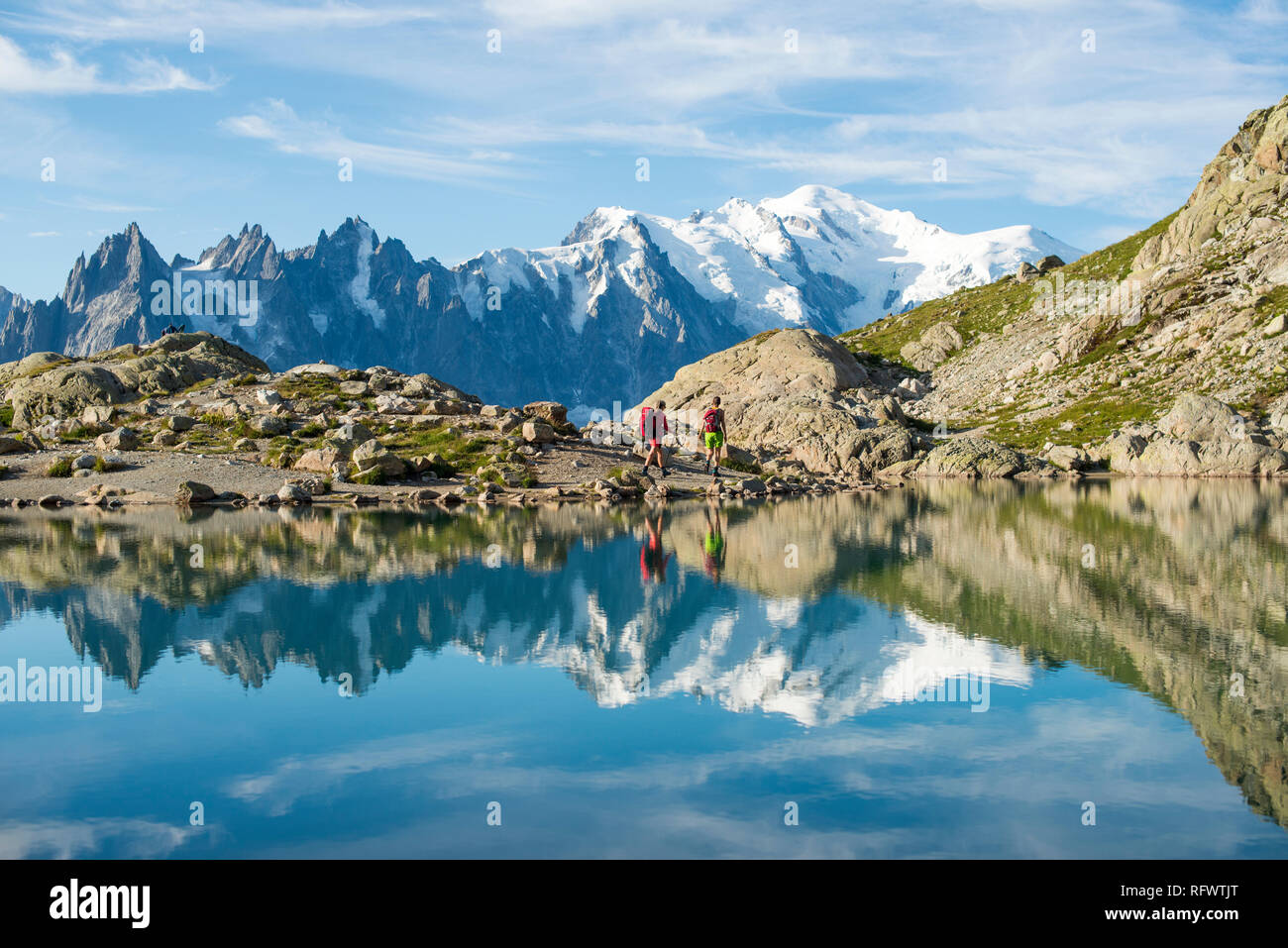 Hikers and the summit of Mont Blanc reflected in Lac Blanc on the Tour du Mont Blanc trekking route, Haute Savoie, Auvergne-Rhone-Alpes, France Stock Photo