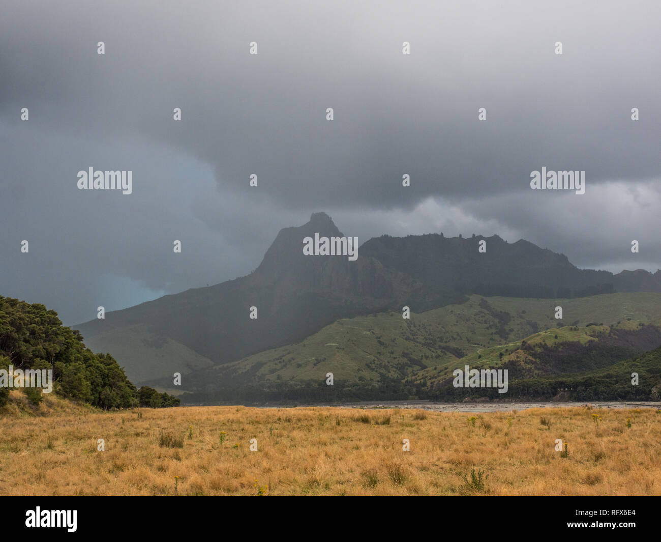 Back country landscape with clouds, rough pasture and rocky hill,  Tapuaeroa Valley, East Cape, North Island, New Zealand Stock Photo
