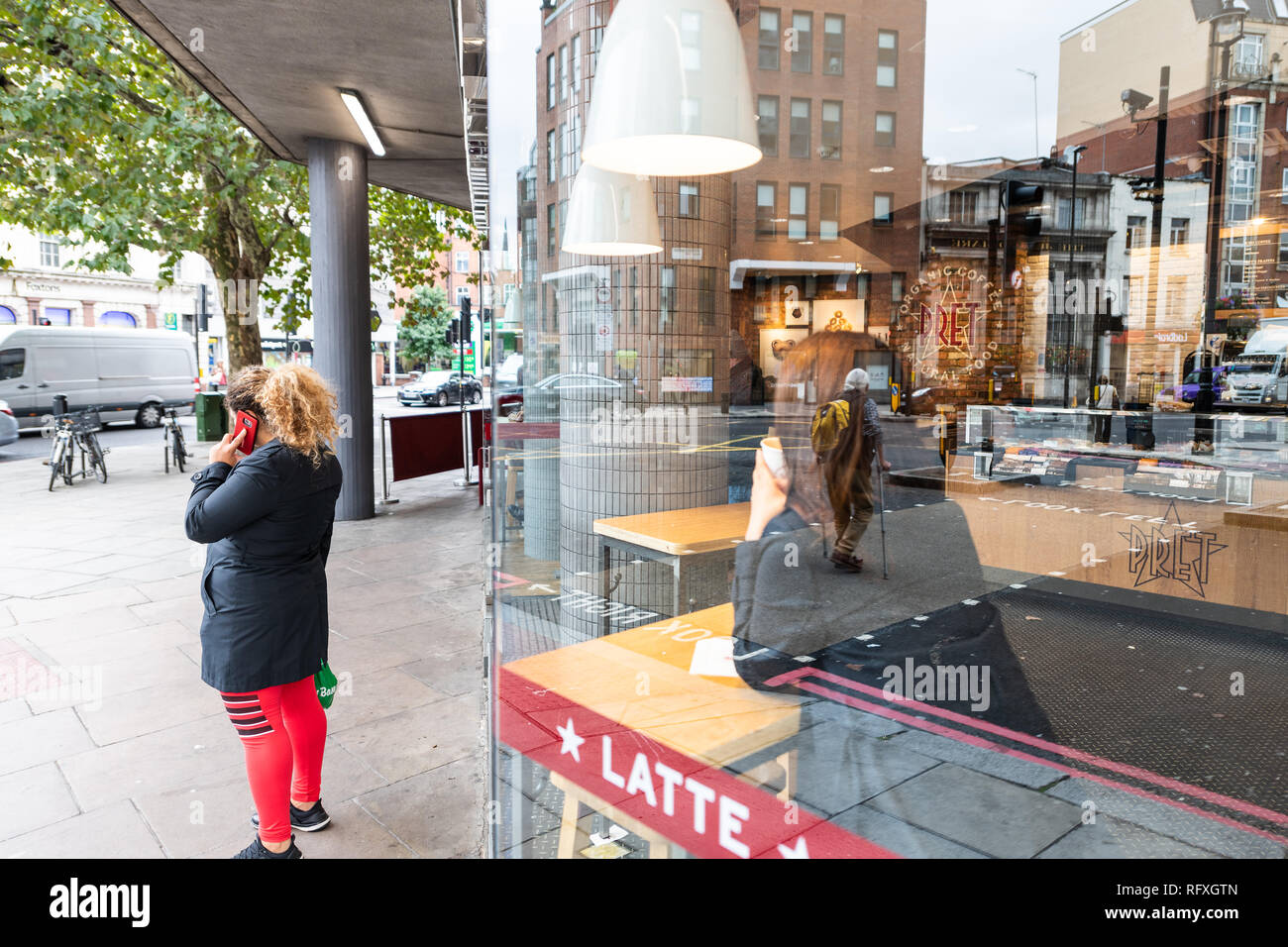 London, UK - September 12, 2018: Neighborhood of Pimlico Victoria with woman standing on sidewalk by Pret A Manger cafe restaurant window reflection Stock Photo