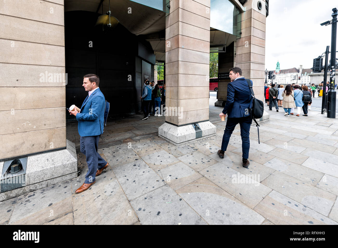 London, UK - September 12, 2018: People walking pedestrians with coffee by Victoria Embankment Thames River and building Stock Photo