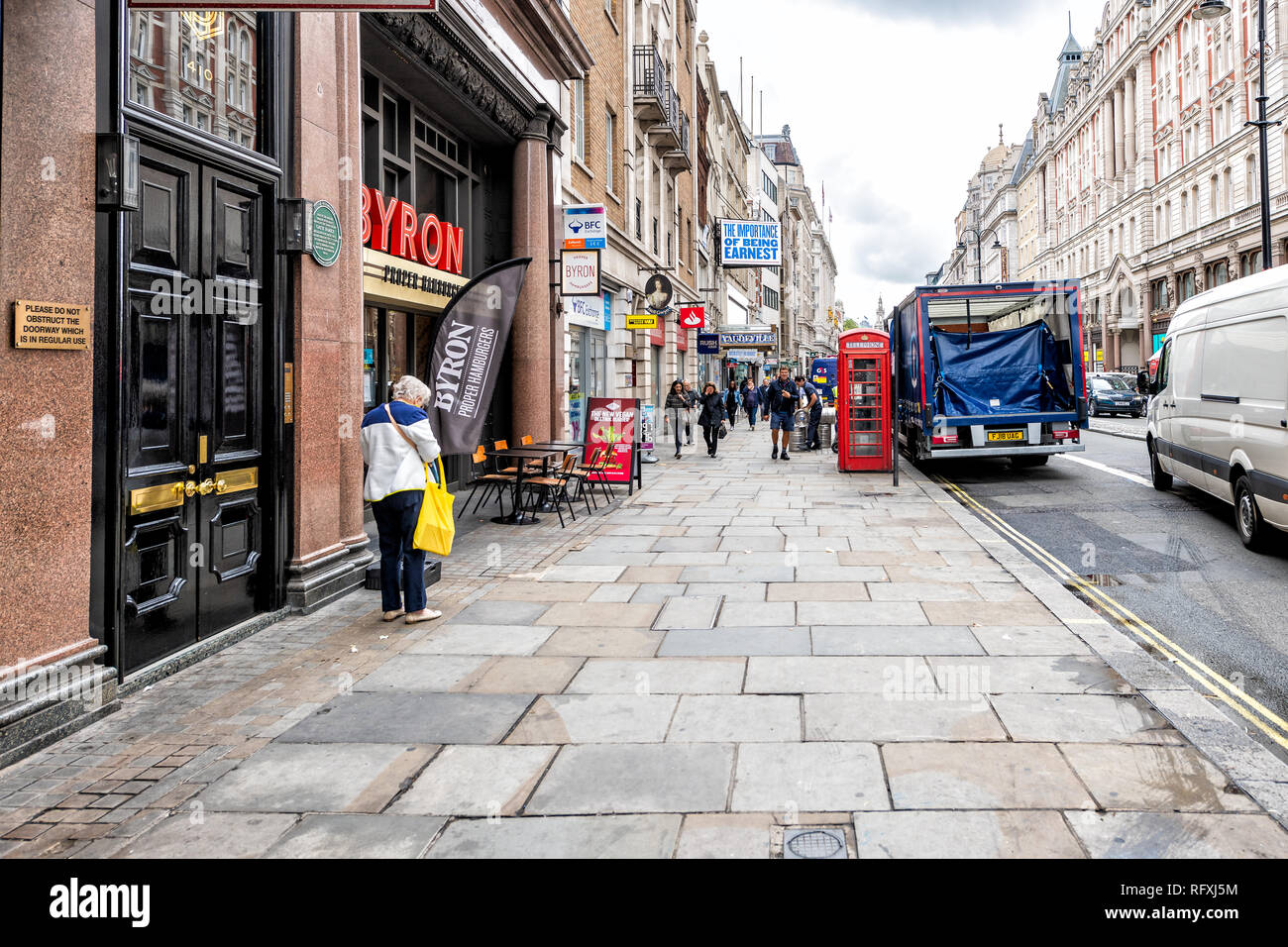 London, UK - September 12, 2018: People walking on street by road with Byron burgers hamburgers restaurant sign and sidewalk in the Strand in Covent G Stock Photo