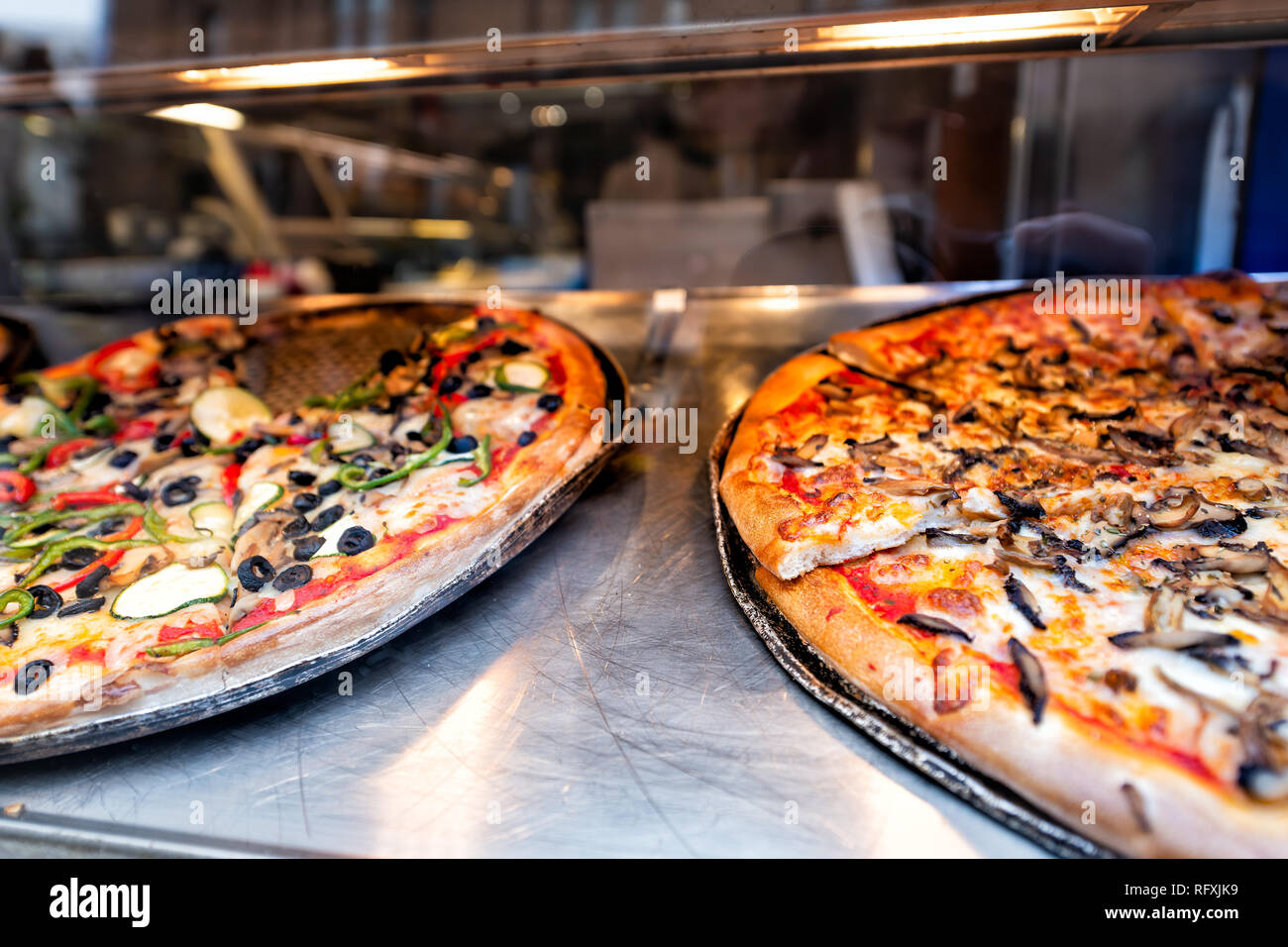 Closeup of fresh large crust pizzas in store cafe on display restaurant