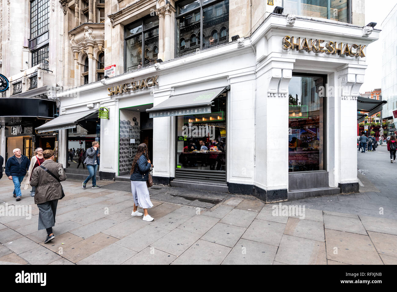 London, UK - September 12, 2018: Sidewalk street shopping at Leicester Square stores during day in city with Shake Shack restaurant Stock Photo