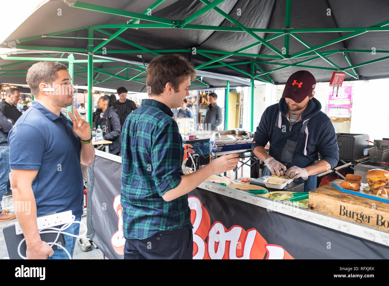 London, UK - September 12, 2018: Famous Brewer Market Street with Soho food stall and vendor outside and people ordering fresh burgers with sign Stock Photo