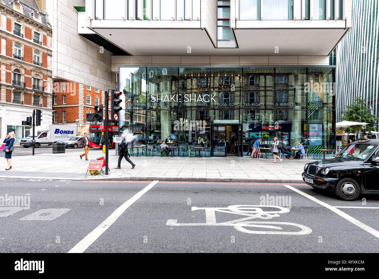 London, UK - September 12, 2018: Buckingham Palace road street during day with people walking on pavement by stores shops and Shake Shack restaurant Stock Photo