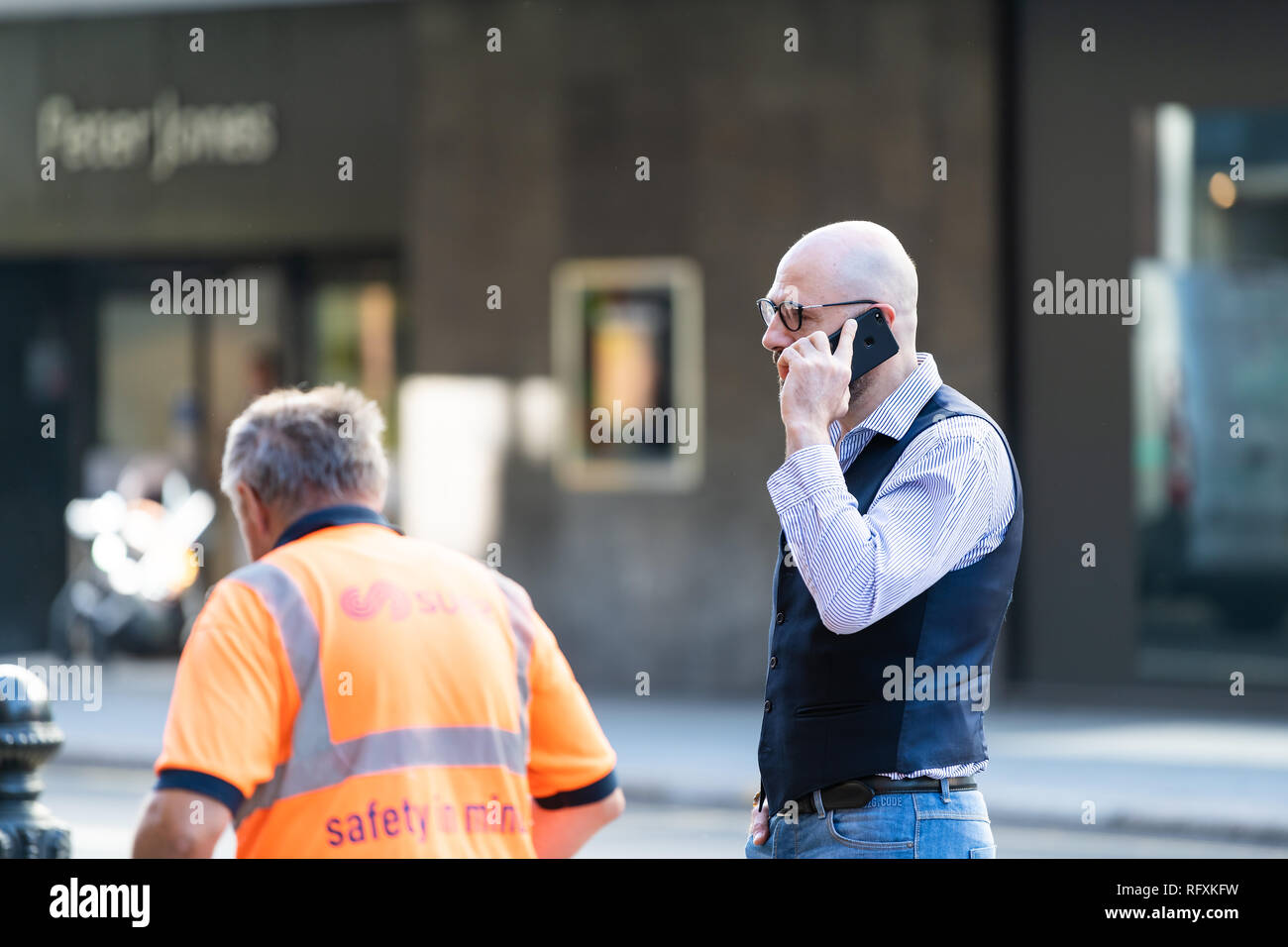 London, UK - September 13, 2018: Business man talking on phone by worker in Chelsea with background of road street Stock Photo