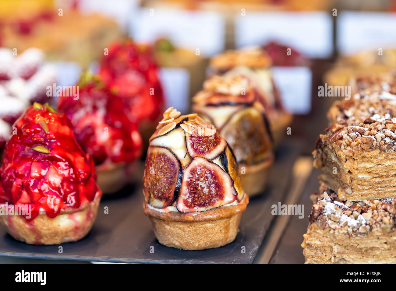 Display of many tarts cupcakes stuffed with cream desserts on trays in