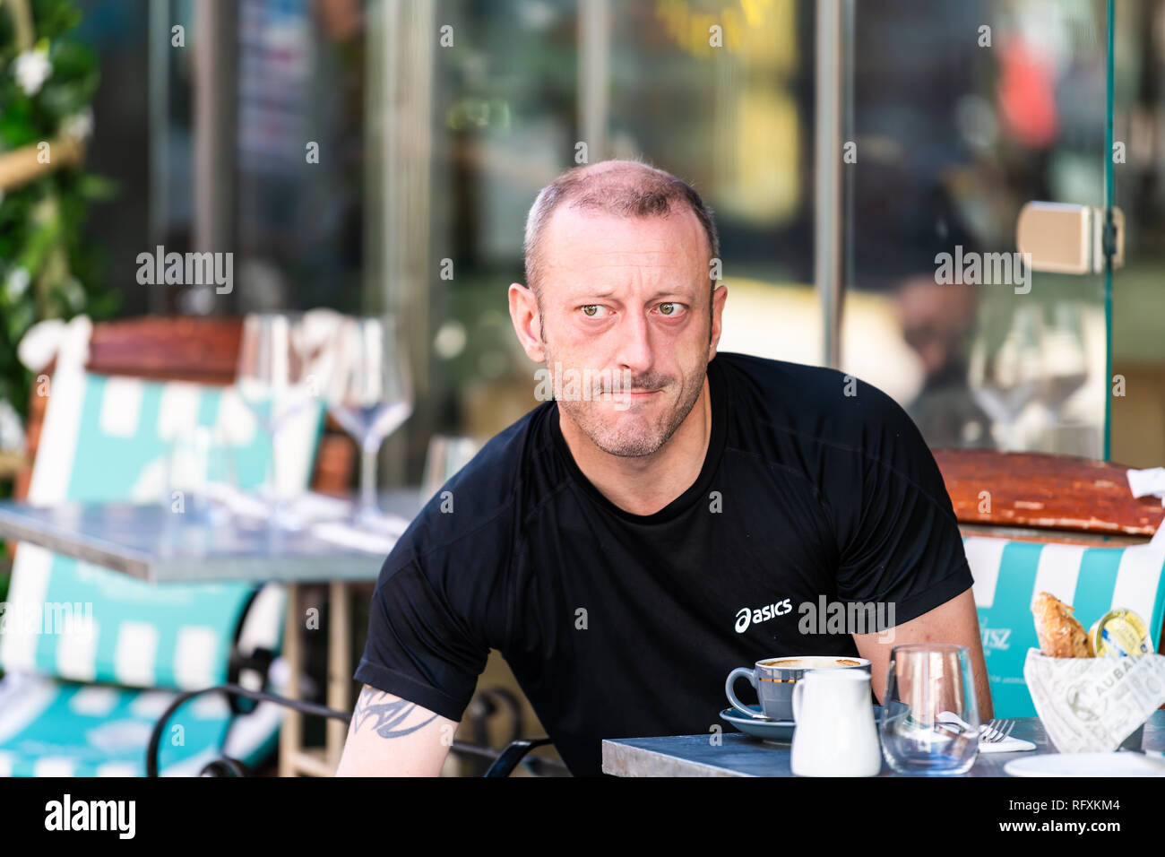London, UK - September 13, 2018: Man sitting at cafe table with coffee at breakfast in outdoor restaurant street sidewalk during sunny day in Chelsea Stock Photo