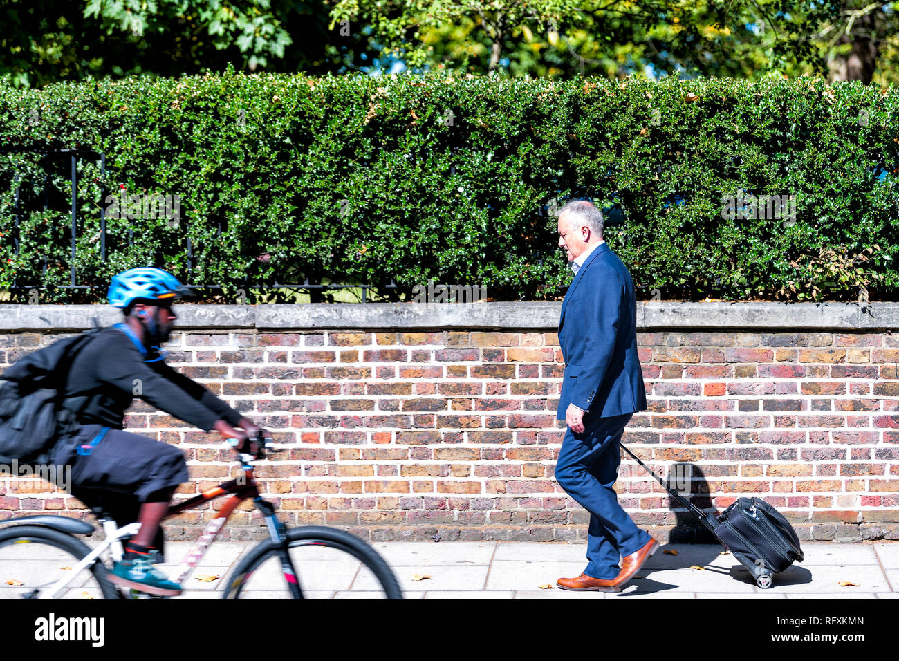 London, UK - September 13, 2018: Street road with one person people man walking with luggage bag pedestrian on sidewalk businessman commute in Kensing Stock Photo