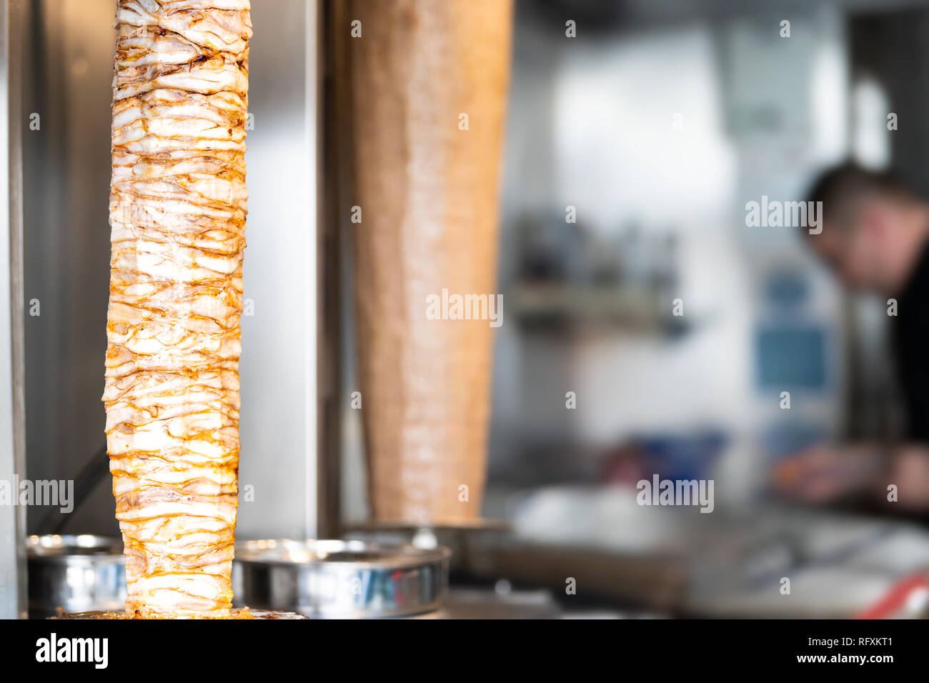 Meat carving grilled kebab closeup with chef in background in building