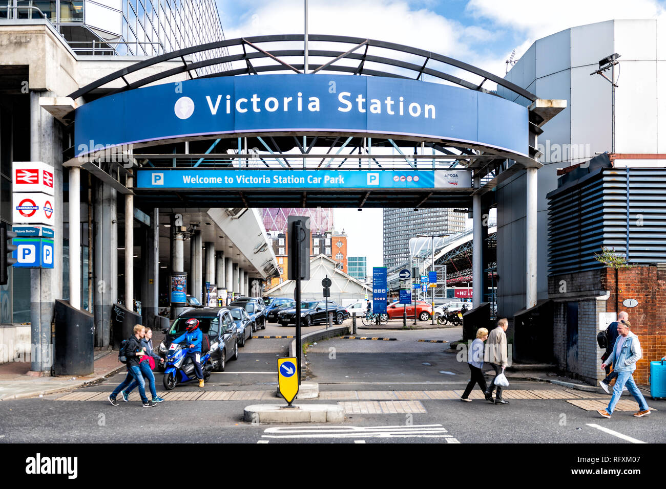 London, UK - September 15, 2018: Blue sign for Victoria Station Car Park parking entrance and people pedestrians walking on pavement Stock Photo