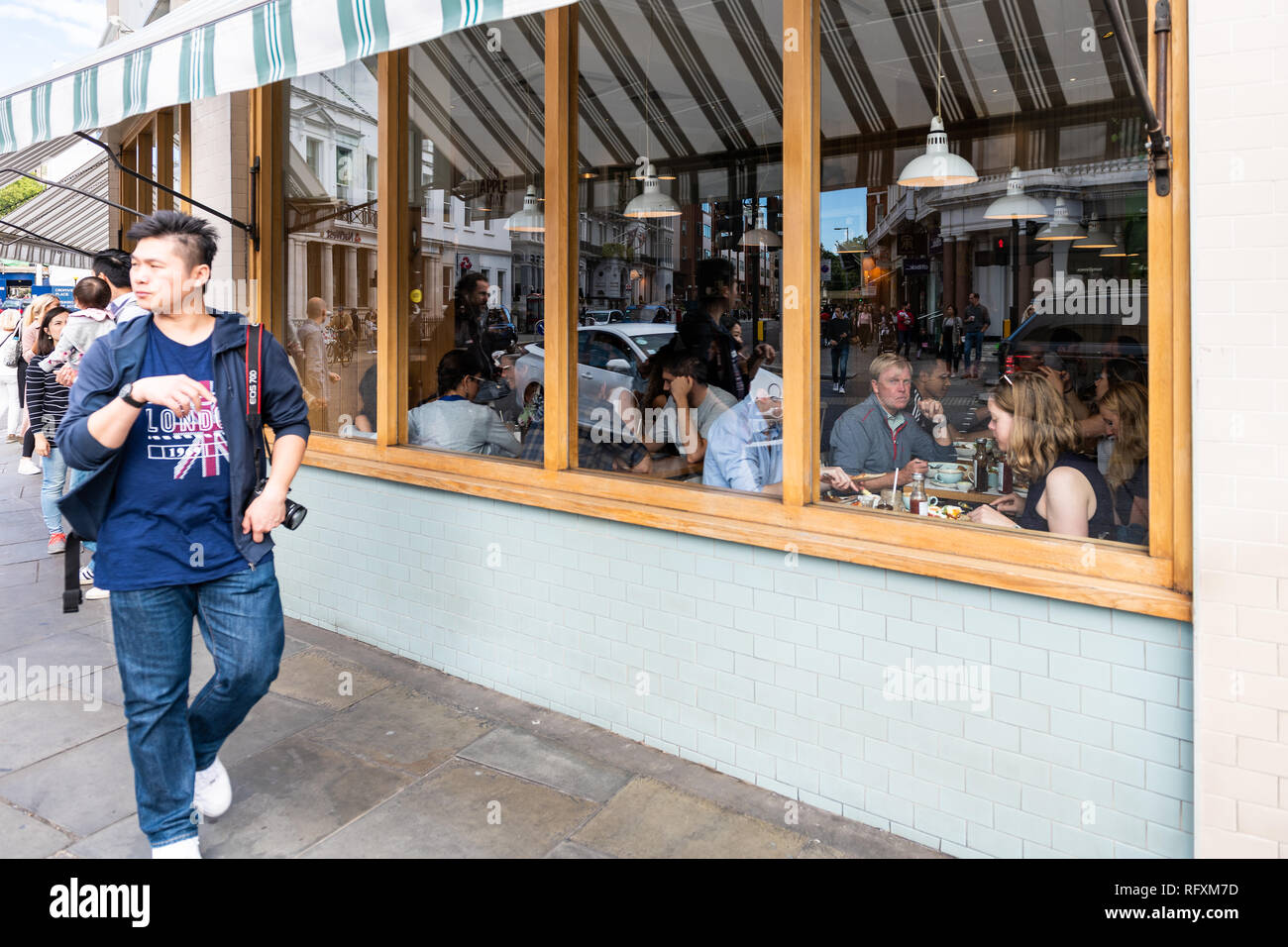 London, UK - September 16, 2018: Neighborhood district of South Kensington street and shopping people walking on sidewalk pavement by cafe restaurant Stock Photo