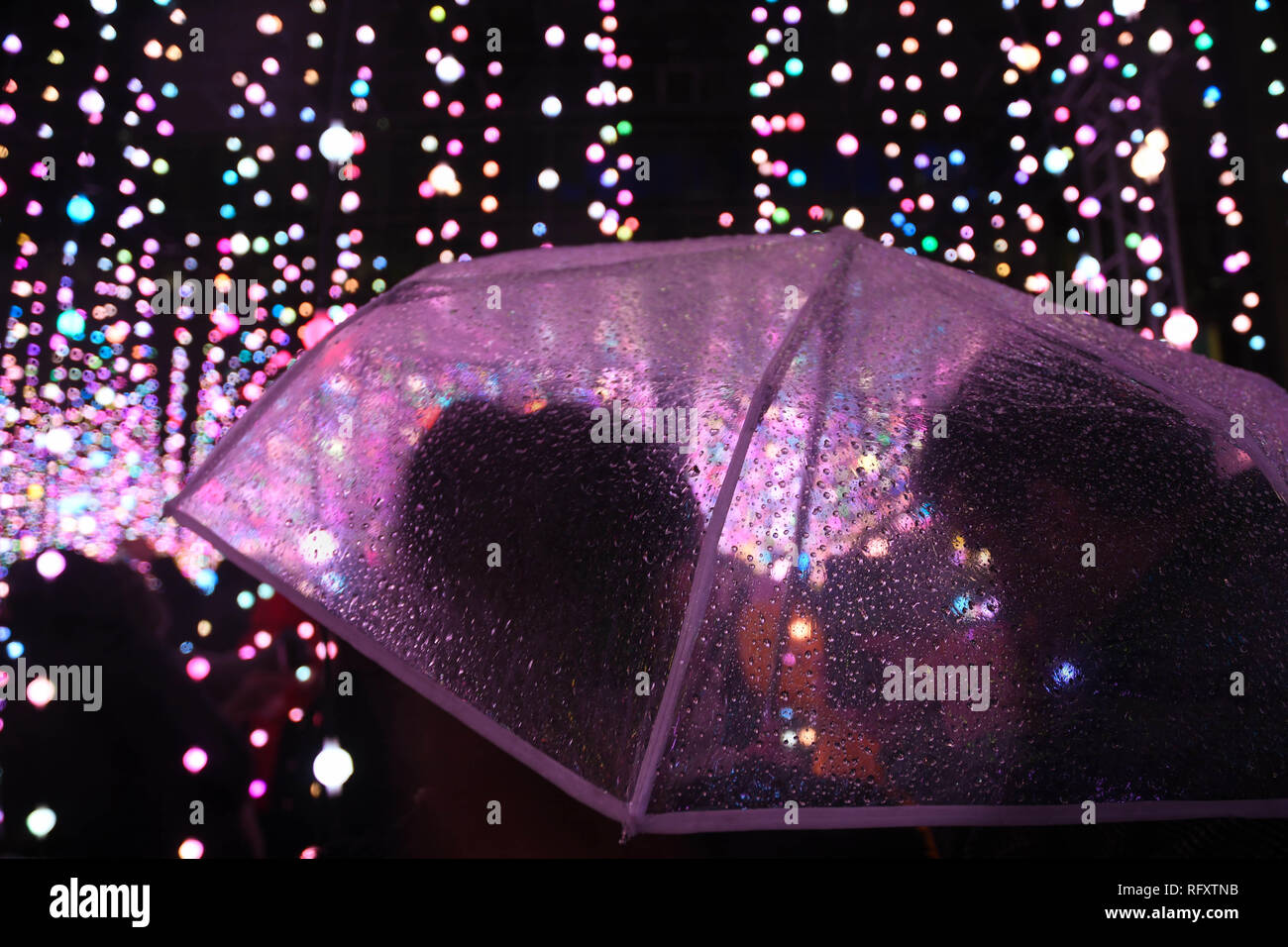 Clear umbrella in the rain and lights at london canary wharf  winter lights festival 2019 Stock Photo