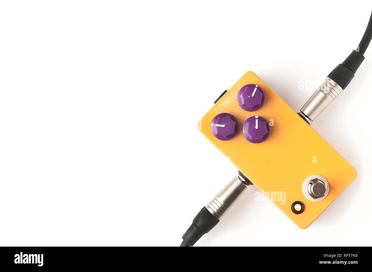 Orange guitar pedal with purple knobs and plugged jacks on white