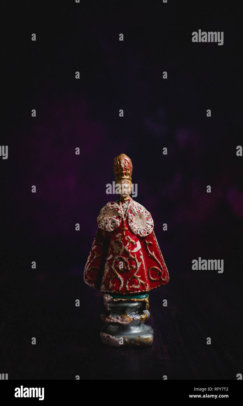 Antique statue of the Infant Jesus of Prague, against a dark background. The original statue is a 16th-century wax-coated wooden statue of the Christ  Stock Photo