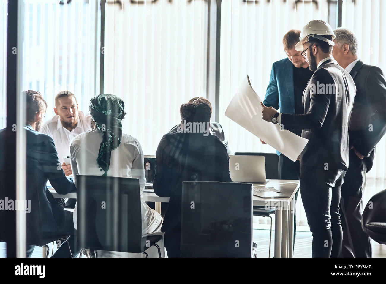 Instructor in protective hat with young people in engineering workshop Stock Photo